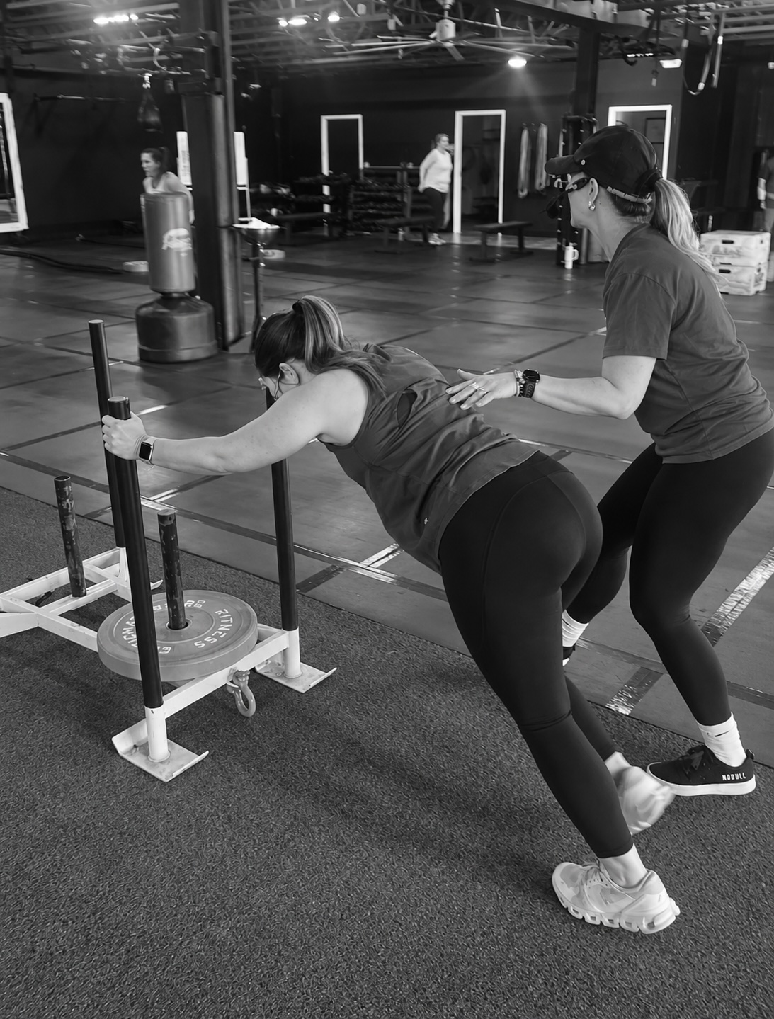 A Fitness Artist coach spotting a member pushing a weighted sled