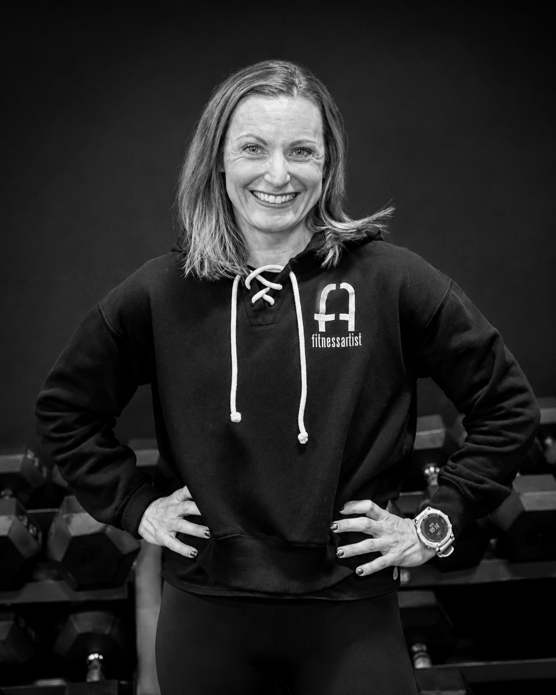 Sarah Hetzer smiling in front of a dumbbell rack