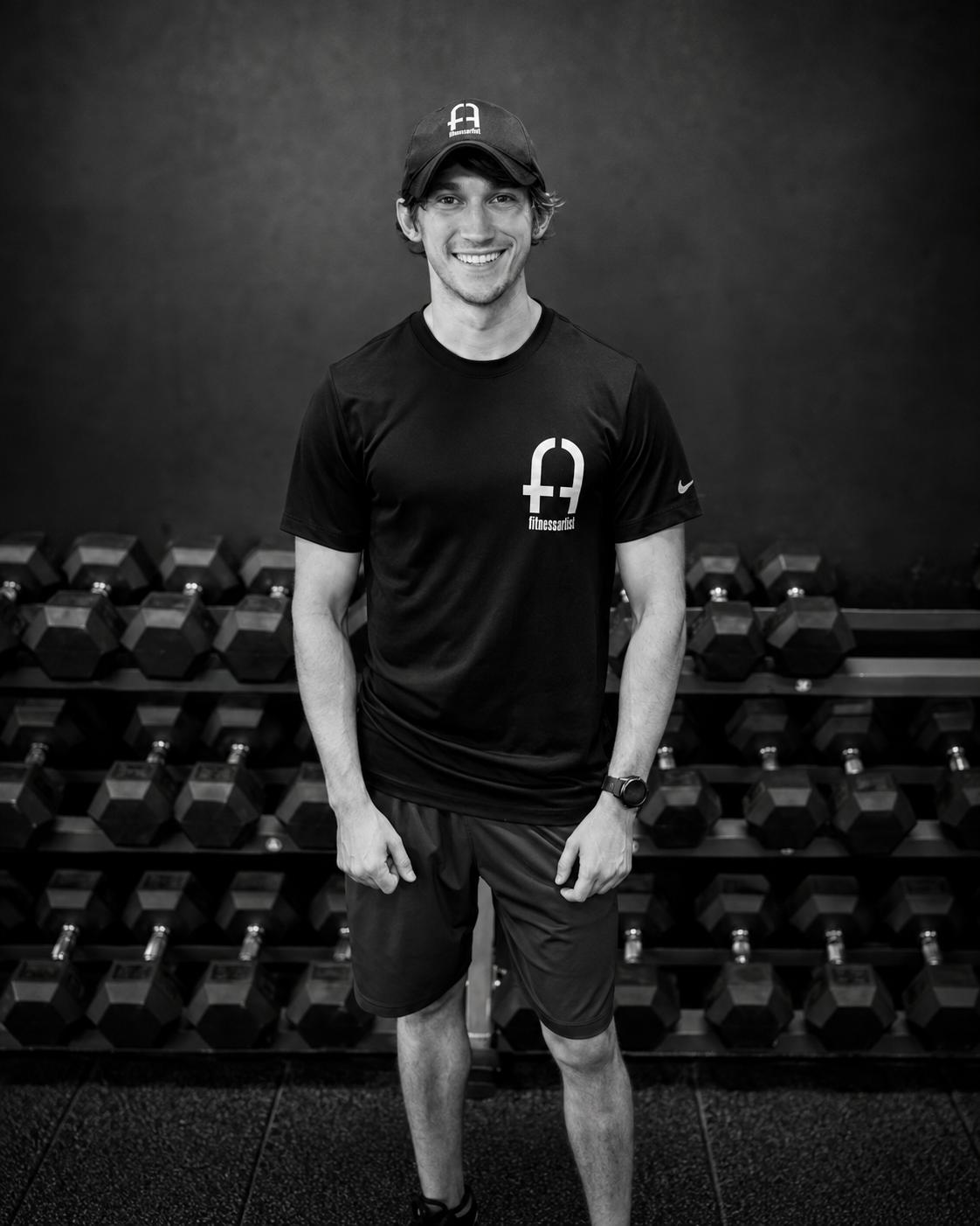 Gabe Cole smiling in front of a dumbbell rack